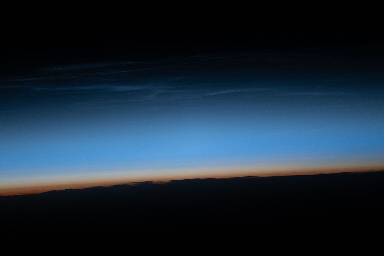Noctilucent clouds lit by the sun just after it has set below the horizon, seen from the International Space Station